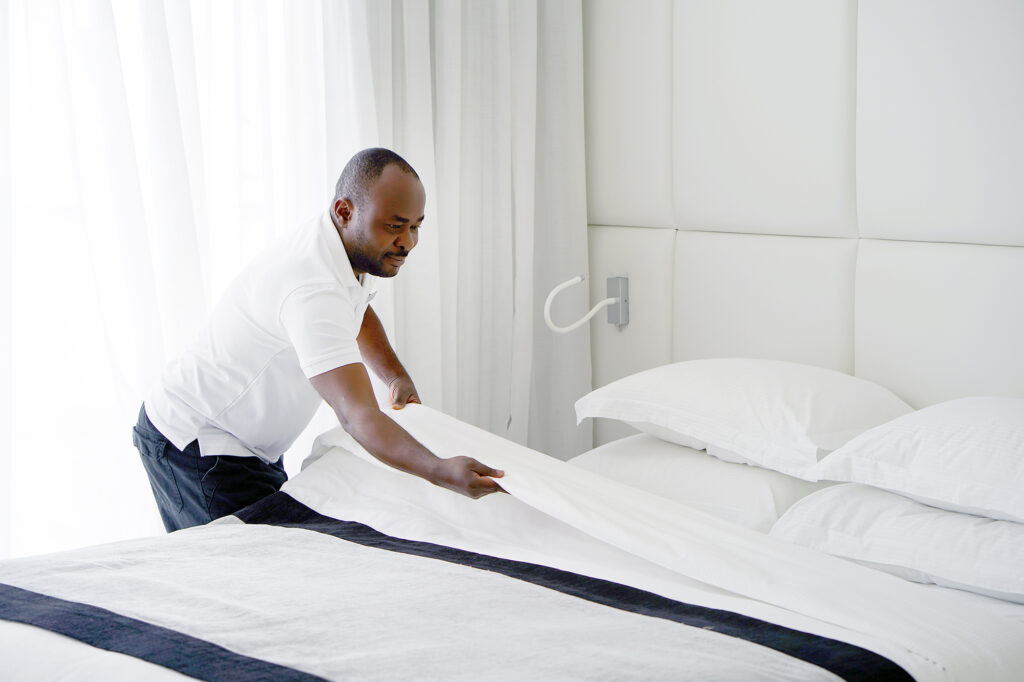 Professional hotel housekeeper making bed in luxury room – representative of hotel staff jobs in Canada